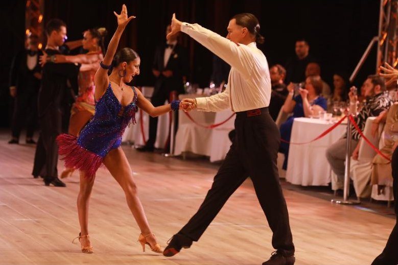 Latin couple on the competition floor beside the gala tables
