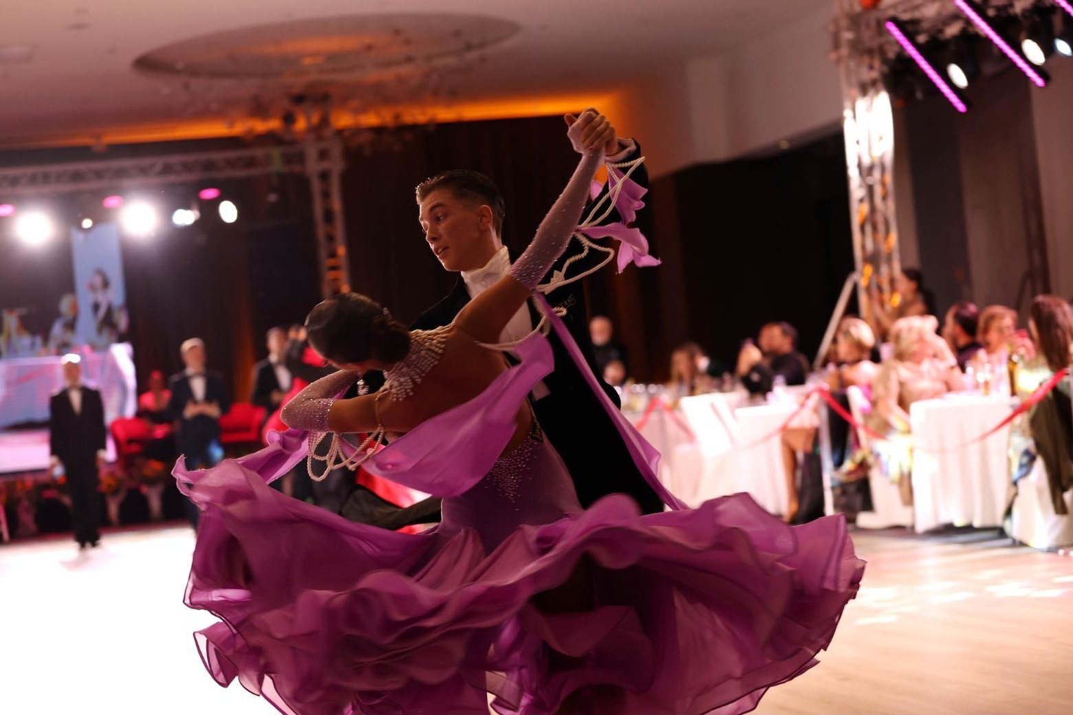 A Standard couple in a violet ballgown turning across the Metechi Palace ballroom floor, 2026